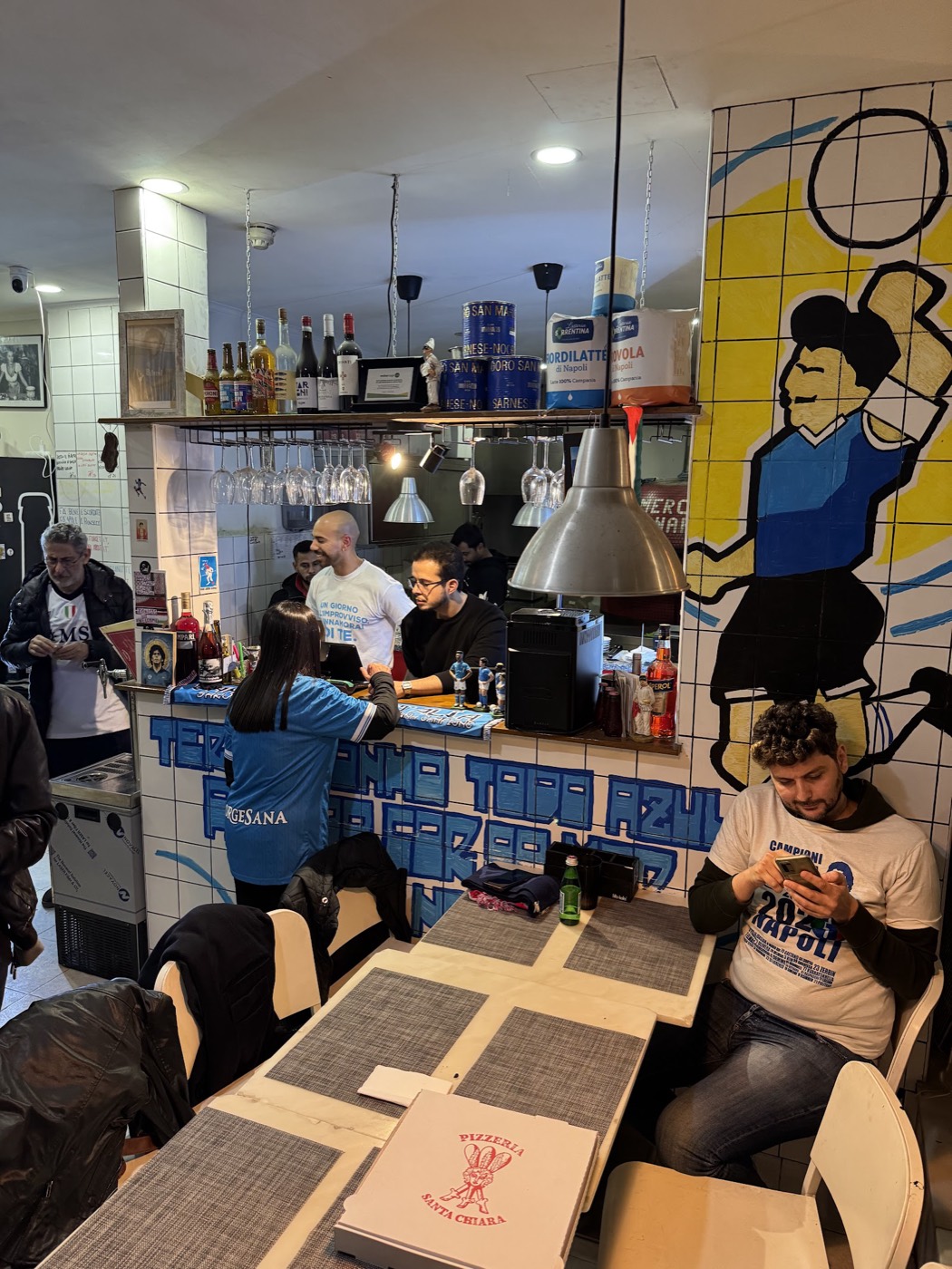 Interior of the pizzeria featuring a large mural of Diego Maradona